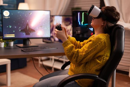 Professional gamer wearing virtual reality headset using wireless controller. Pro esport team player streamer playing gaming tournament on powerful RGB computer, using modern streaming technology.