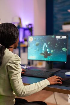 African gamer trying to relax playing space shooter online championship. Competitive cyber player woman performing videogame tournament use professional joystick.