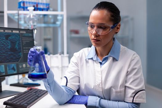 Chemist woman analyzing liquid solution holding medical glass flask researching disease dna expertise results. Scientist doctor developing biochemistry diagnostic working in hospital laboratory