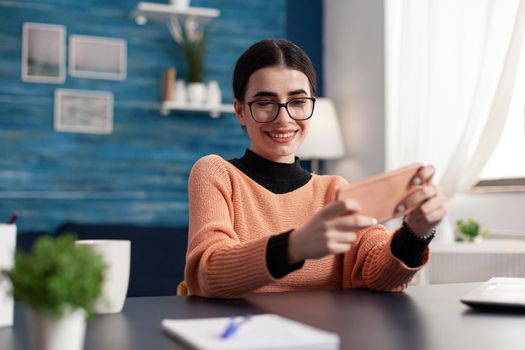 Gamer playing online entertainment videogames with multiplayer during cyberspace competition using isolated display of phone. Player sitting at desk in living room holding device in horizontal mode