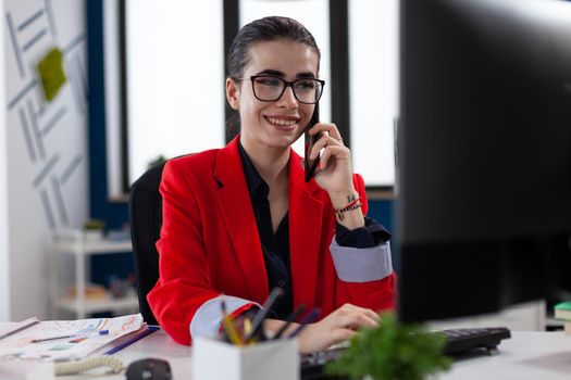 Businesswoman in office workplace privide help consulting client, distantly by mobile phone. Entrepreneur looking at document on computer screen. during phone conversation.