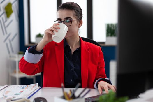 Businesswoman taking a sip of coffe working in corporate office workplace , making financial analysis expertise. succesful Executive manager taking a dose of caffeine.