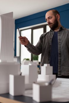 Architect man looking at design in professional office for inspecting maquette building model plan. Caucasian person engineering for modern industrial construction project