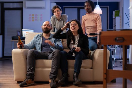 Group of diverse colleagues losing game with vr glasses on console tv while using joystick controller. Multi ethnic team having fun entertainment enjoyment at happy indoors celebration