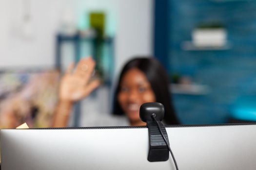 African american student waving teacher discussing university lesson course during online videocall meeting conference working remote from home. Selective focuse on computer webcam