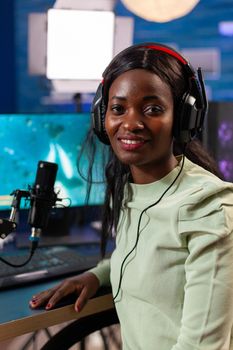 Happy esport african gamer during live championship in room with neon light. Streaming viral video games for fun using headphones and keyboard for online championship.