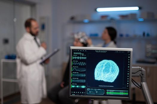 Neuroscience doctor holding clipboard showing treatment against brain disease to patient with eeg headset. Woman sitting in neurological scientific laboratory treating nervous system dysfunctions.