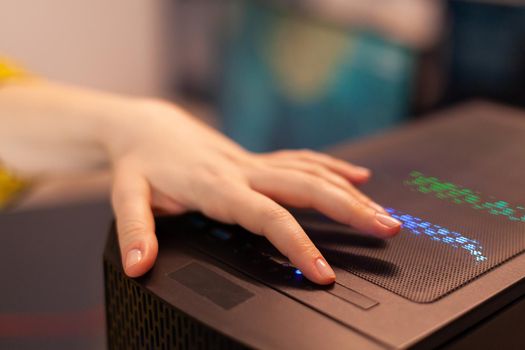 Woman gamer power on computer unit preparing for gaming tournament. Cyber performing on powerful personal computer in stylish room starting to play online shooter game.