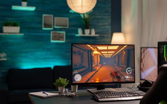 Close up of empty gaming home studio with neon lights equipped with professional powerful computer, headphones, RGB keyword, mouse