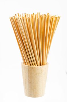 Wheat straw for drinking water in wooden glass on white background. Zero waste concept.