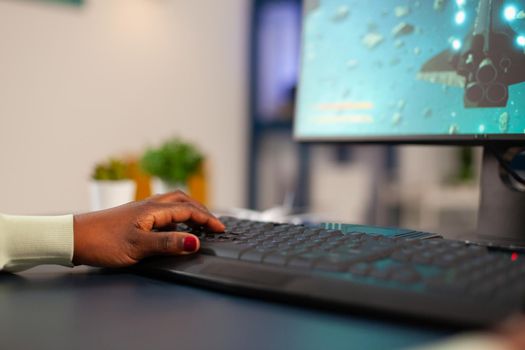 Black professional esports competitive gamer using game keyboard Close up of african woman hand playing online esport video games space shooter using keyboard.