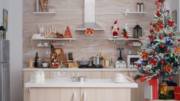 Empty xmas decorated culinary kitchen with nobody in it is ready for traditional christmas celebration. On table standing traditional homemade cookie dessert ingredients with milk glass