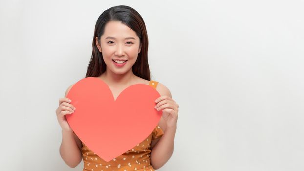 Attractive young smiling woman holding big red heart in hands isolated on white background. 