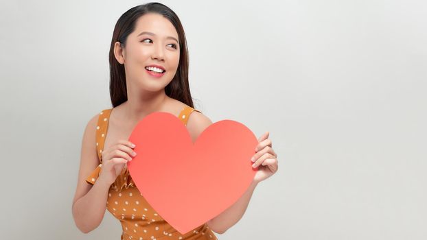 Woman holding big red heart on white background