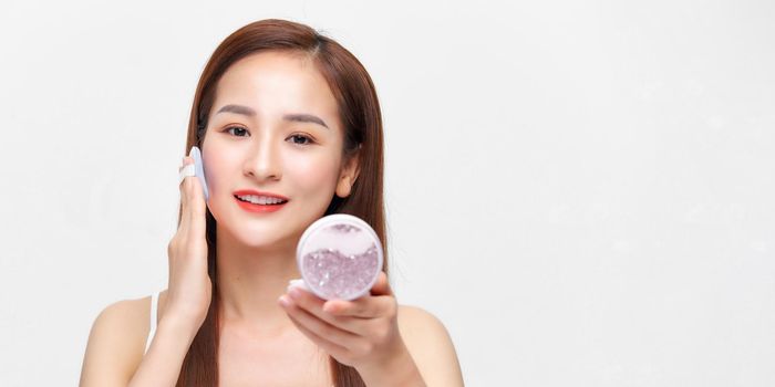 Portrait of beautiful asian woman applying powder puff at cheek makeup of cosmetic