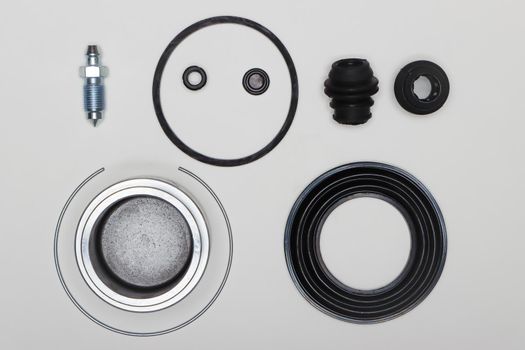 Caliper repair kit, rubber gaskets, oil seals, piston, fitting. Set of spare parts for car brake repair. Details on white background, copy space available. UHD 4K.