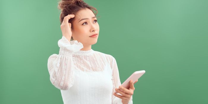 Young woman using smartphone serious face thinking about question, very confused idea