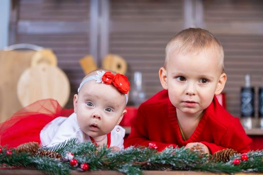 Little brother and newborn sister in a Christmas interior. Funny little children with Christmas decorations.