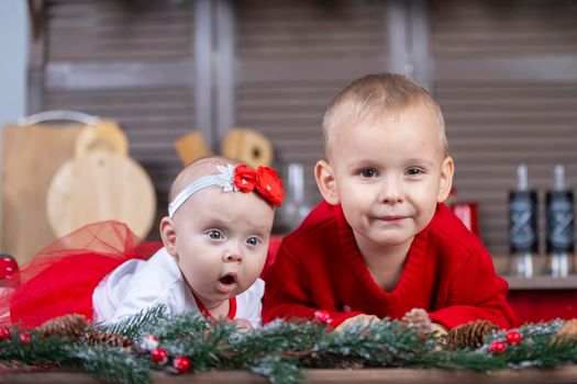 Little brother and newborn sister in a Christmas interior. Funny little children with Christmas decorations.