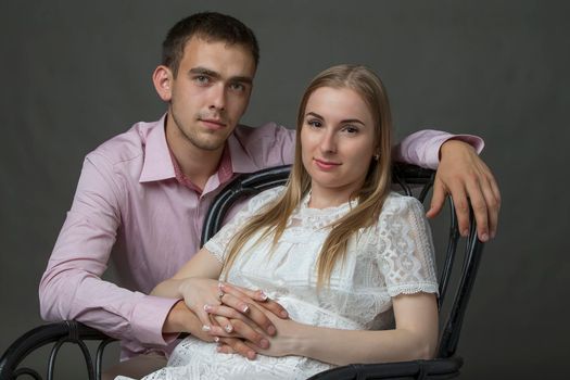 Classic portrait of a young woman and man on a gray background.