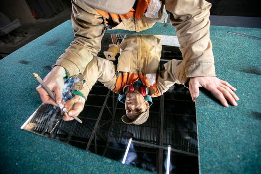 A worker cuts glass with a glass cutter. Furniture manufacturing.