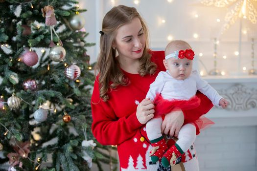 Mom and child at Christmas. A young woman with a newborn daughter on the background of Christmas interiors.