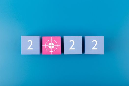 New Year 2022 blue minimal business and setting goal concept. Modern elegant composition with blue toy cubes with written 2022 numbers and target on blue background. 