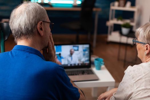Elderly couple using video call for dentist advice against pain with online conference for healing treatment prescription. Senior mature patient on telemedicine teeth consultation