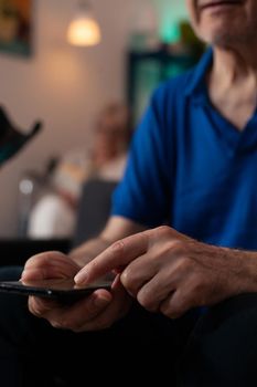 Close up of old mature man hand typing on smartphone screen display using modern technology with online internet connection. Senior person sitting at home learning digital communication