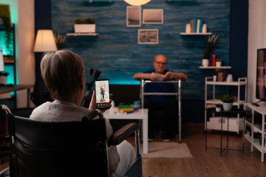 Woman in wheelchair calling doctor using video call technology on smartphone sitting at home asking for medical advice. Caucasian disabled couple with transportation problems