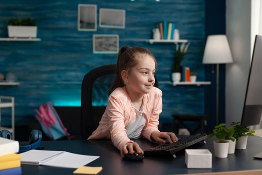 Primary schoolgirl looking at computer monitor for online class lecture on internet connection and technology. Smart caucasian student on digital communication lessons and study meeting