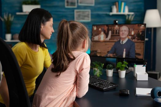 Little kid and mother doing virtual meeting with relatives on online internet website. Family using digital video call modern technology to talk to grandpa at home social distancing