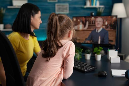 Smart school girl and mom on online conference video call using internet connection computer monitor screen to talk to distant grandfather. Caucasian family meeting on virtual website app