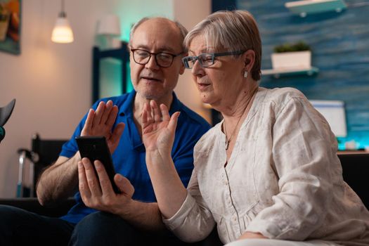 Retired people on smartphone video call together using wireless internet online connection for communication with family. Caucasian senior married couple on technology device gadget