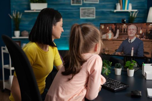 Little kid and mother doing virtual meeting with relatives on online internet website. Family using digital video call modern technology to talk to grandpa at home social distancing