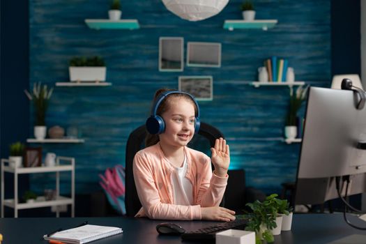 Modern school pupil paying attention to online class while using technology computer internet website and headphones. Clever girl working on education knowledge and digital communication