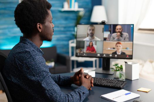 Man of african ethnicity using conference webcam communication to connect via internet with coworkers while working from home. Black person remote worker chatting about job duties