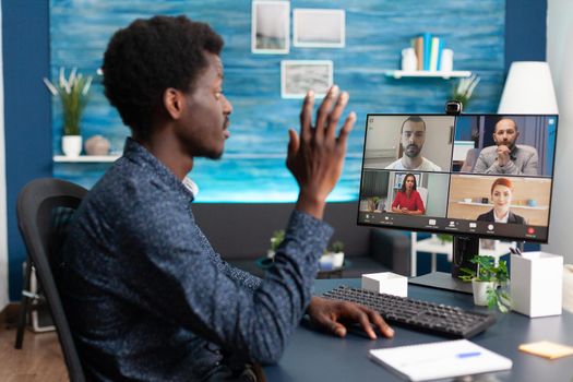 African american man talking on online video call waving to colleagues using webcam communication. Black person working from home keeping distance while using digital technology