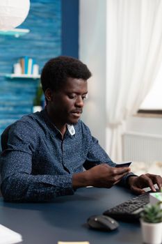 E commerce consumer shopping online with credit card, introducing number information on computer. Black african american man buying via internet transaction concept using digital payment