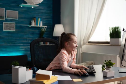 Smart little pupil looking at computer monitor screen at home for online class lesson. Caucasian student paying attention to lecture studying for elementary exam work and knowledge