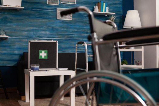 Hospital medical bag equipment standing on table in empty living room with nobody in it during healthcare therapy recovery. Social support nursing services at home. Rehabilitation assistance service