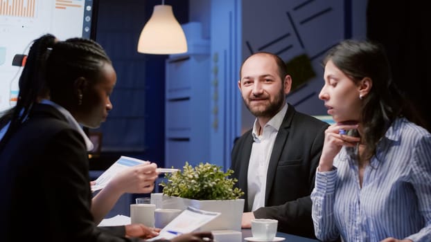 Portrait of smiling manager man looking into camera working at company strategy in meeting office room late at night. Diverse multi-ethnic business teamwork brainstorming management expertise