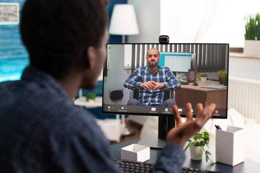 African american man chatting using online internet communication while working from home office. Black remote worker on video call conference with boss talking about business plan