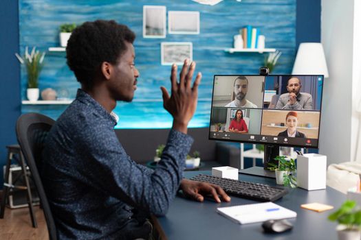 African american man talking on online video call waving to colleagues using webcam communication. Black person working from home keeping distance while using digital technology