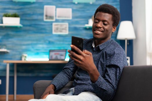 Black man greeting colleagues on video call conference in living room. Working from home african american remote worker in distance communication chat, learning about business project