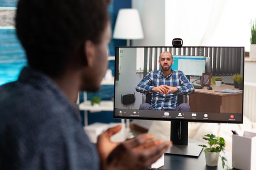 African american man on online video call communication while working from desk office at home. Black worker on internet conference talking with colleague about business job details