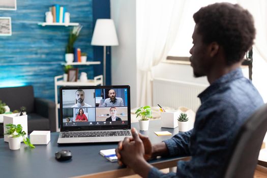 Black man remote employee working from home taking online office call with partners and colleagues. Computer user from desk on video internet conference via webcam conference