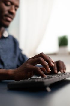 Black african american person typing on PC keyboard, working from home. Remote computer user, african american businessman doing job task in marketing and communication industry