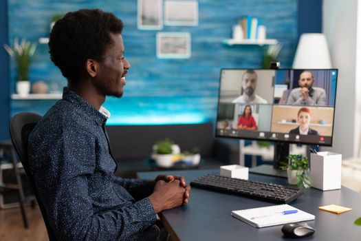 Black man doing online conference video call to talk via internet with colleagues while working from home. African american person remote worker at desk using computer technology