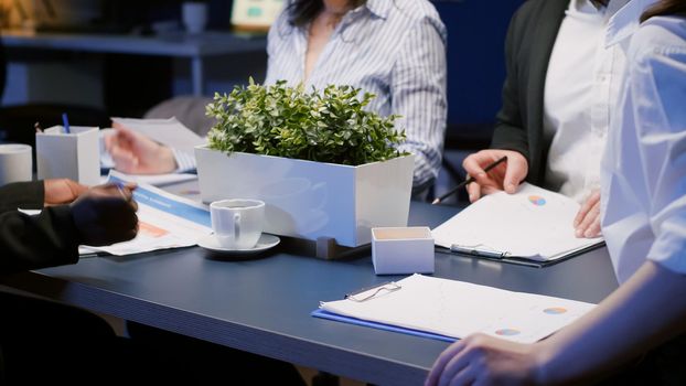 Selective focus of diverse multi-ethnic businesspeople working late at night analyzing financial strategy solving corporate statistics. Business teamwork working in office meeting room in evening